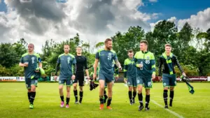 Jalgpallurid rohelises vormis kõndimas jalgpalliväljakul pärast treeningut või matši.