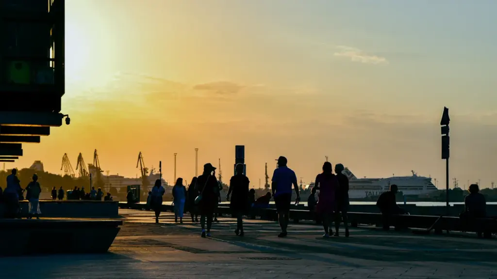 Inimesed jalutamas Noblessneri promenaadil Tallinna kauni kuldse päikeseloojangu ajal.