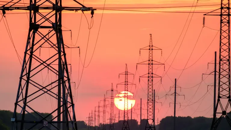 Kõrgepingeliinid ja elektripostid päikeseloojangu ajal Eestis, kujutades energiavõrku ja elektribörsi teemat.