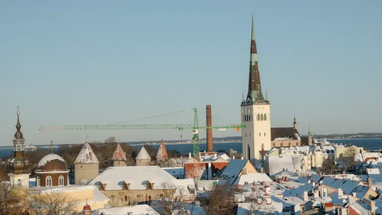 Panoraamvaade lumistele Tallinna vanalinna katustele ja kirikutornile talvisel ajal.