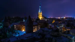 Tallinna vanalinn valgustatud torniga sumedas õhtuses õhkkonnas, vaade üle ajalooliste katuste.