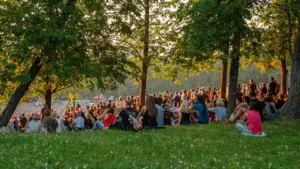 Inimesed naudivad suvisel õhtul kontserti Tallinna lauluväljakul päikeseloojangu kuldse valguse käes.