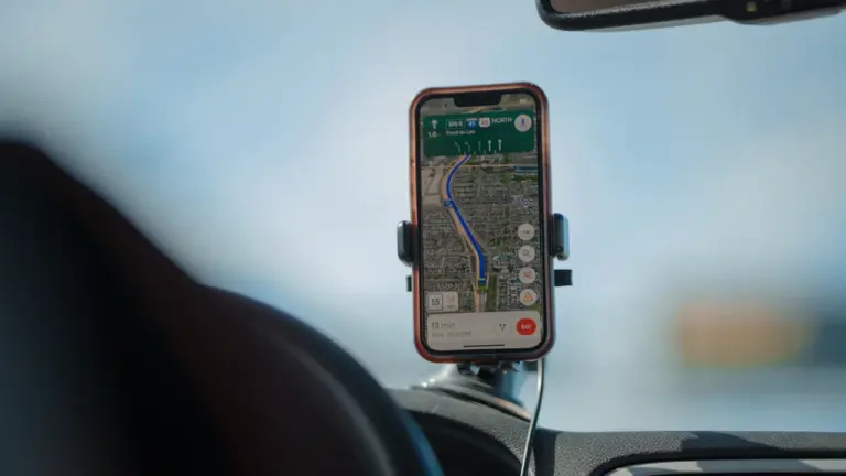 Nutitelefoni navigatsioonirakendus autohoidikus näitamas marsruuti ja teekonda ekraanil.