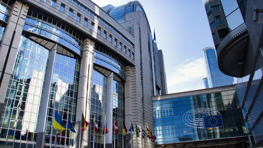 Euroopa Parlamendi moodne hoone koos lehvivate Euroopa Liidu lippudega selge taeva all.