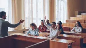 Õpilane tõstab käe õppejõu loengus, et küsida küsimust auditoorses õppekeskkonnas.
