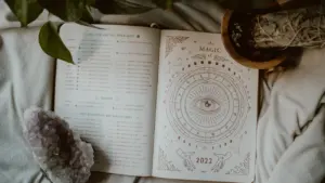 Avatud horoskoobiraamat kristallide ja taimedega rahulikus koduses atmosfääris pühapäeval.