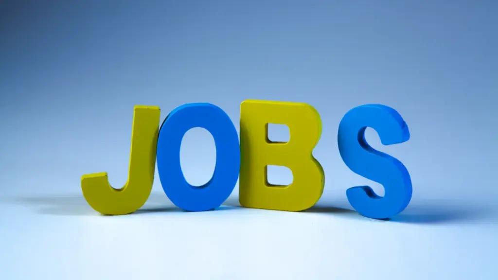 Puidust klotsidest moodustatud sõna 'JOBS' helesinisel taustal töötuse teemalise artikli jaoks.