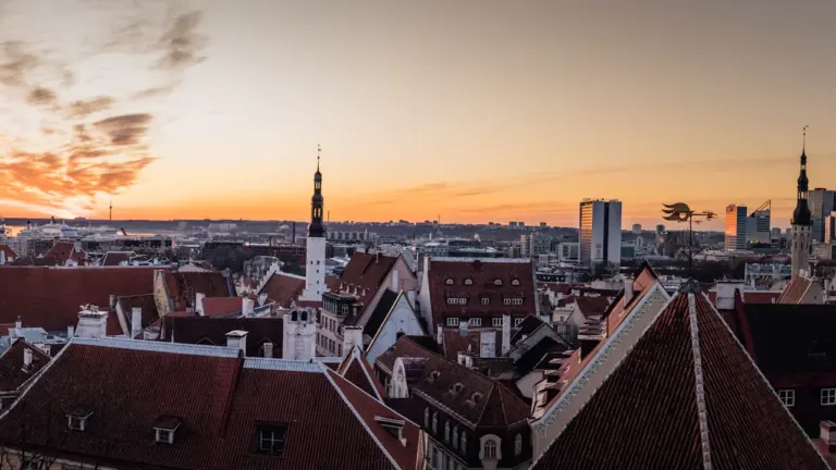 Panoraamvaade Tallinna vanalinna ajaloolistele katustele ja kirikutornidele päikeseloojangu ajal.